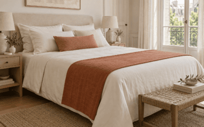 Chemin de lit en lin terracotta disposé au pied d’un lit avec une parure crème